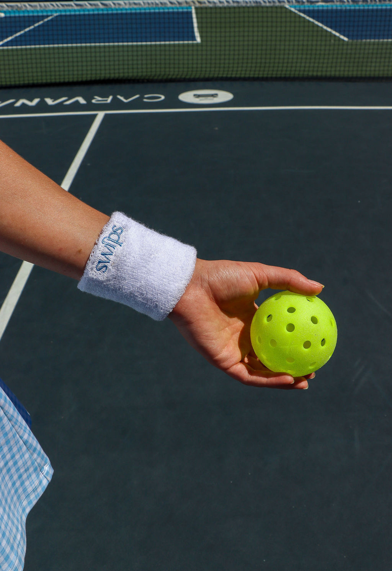 Close-up of a Swips wristband and pickleball on court