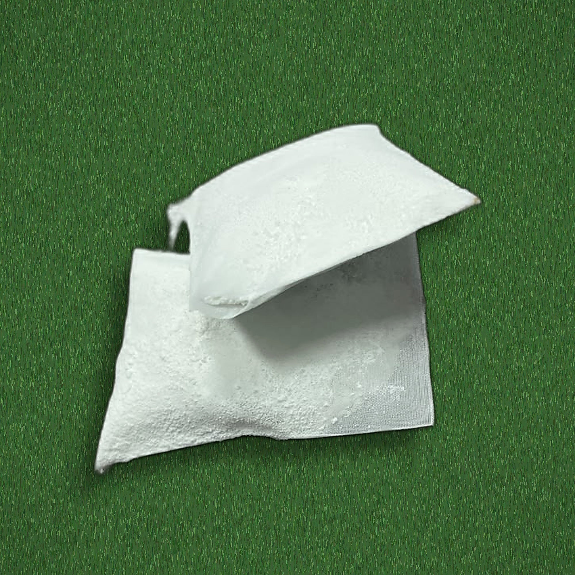 Two Swips rosin inserts out of their sachets on turf, showing the porous packets that drop into the band